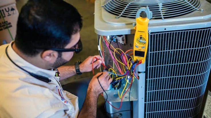 Technician testing air conditioner wiring with a clamp meter