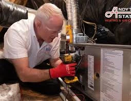 Technician working on a heating unit connected to ventilation ductwork